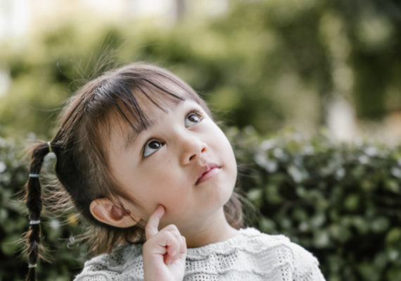 Little girl looks to sky and ponders